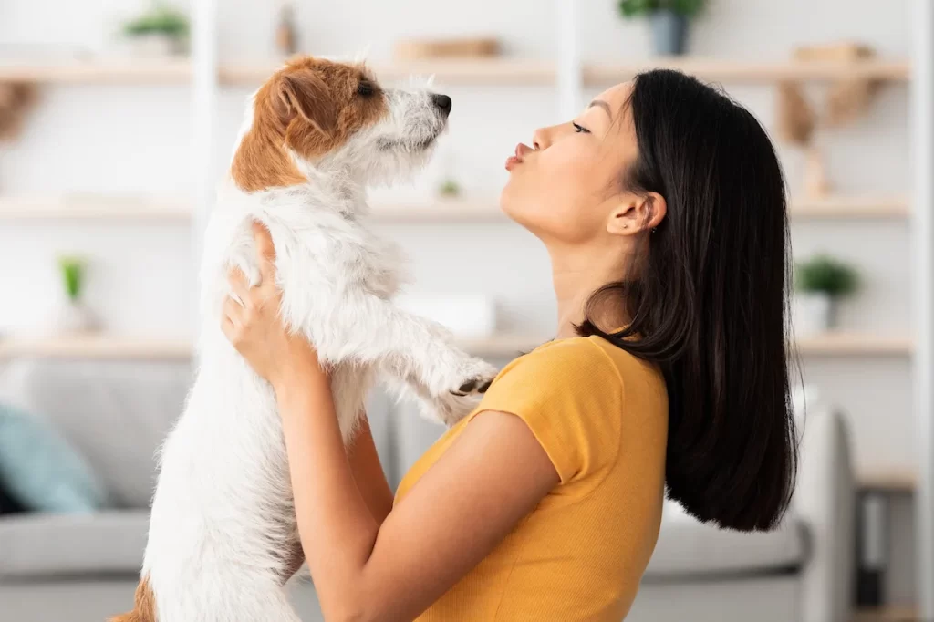 Woman playing and kissing dog